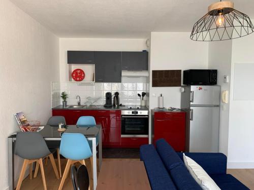 une cuisine avec des placards rouges et une table avec des chaises bleues dans l'établissement Le Petit Bruxelles au calme, à Toulouse