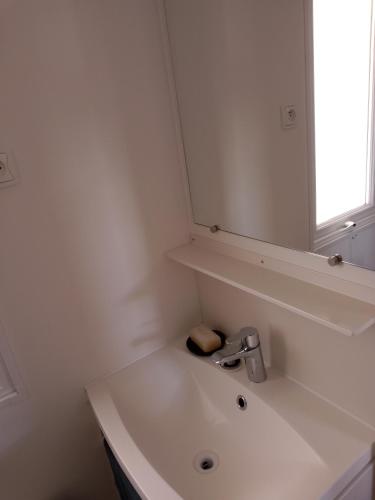 une salle de bain blanche avec un lavabo et un miroir dans l'établissement Mobil home, à Sérignan