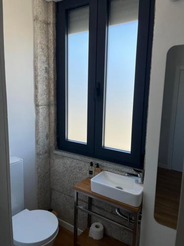 a bathroom with a toilet and a sink and two windows at Ameixial Suites in Porto