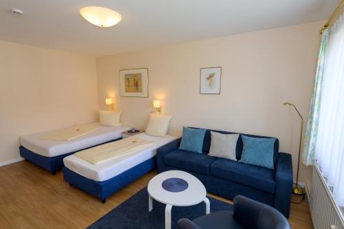 a room with two beds and a couch and a table at Bremer Apartmenthotel Superior in Bremen