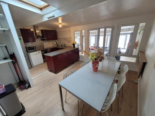 une cuisine et une salle à manger avec une table et des chaises blanches dans l'établissement Super F3 coconing tout équipé 5 personnes, à Beaumont-sur-Oise