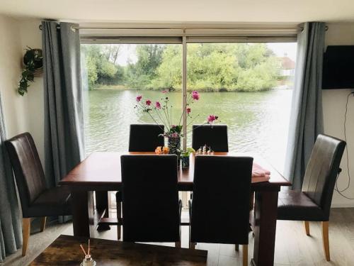 a dining room table with chairs and a large window at RIVER RETREAT- near Holloway U, Thorpe Park and Heathrow airport in Thorpe