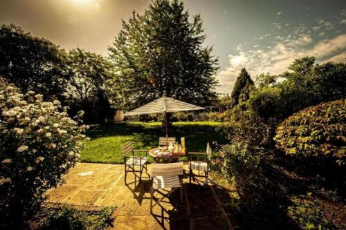 a table and chairs with an umbrella in a garden at RIVER RETREAT- near Holloway U, Thorpe Park and Heathrow airport in Thorpe