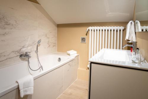 a bathroom with a sink and a bath tub at La petite maison du Gastronome in Paliseul