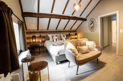 a bedroom with a bed and a couch and a chair at La petite maison du Gastronome in Paliseul
