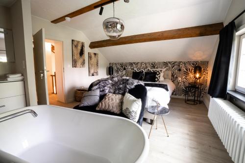 a bathroom with a bath tub and a bedroom at La petite maison du Gastronome in Paliseul