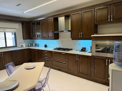 a kitchen with wooden cabinets and a table with chairs at Star of Um Uthayna Furnished Apartment in Umm Uthainah