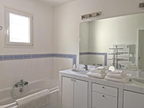 La salle de bains blanche est pourvue d'une baignoire, d'un lavabo et d'un miroir. dans l'établissement Maison 3 étoiles Piscine chauffée Centre Var, à Gonfaron