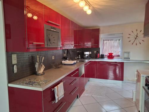 une cuisine avec des placards rouges et une horloge murale dans l'établissement Havre de paix, à Malansac