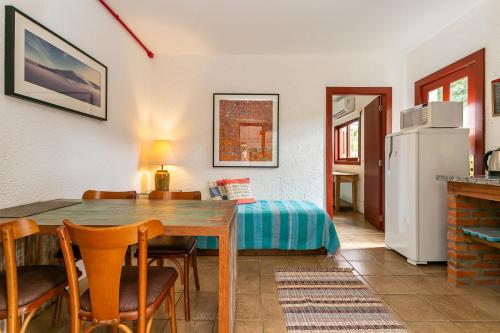a room with a table and a bed and a refrigerator at Pousada Casa da Lagoa in Florianópolis