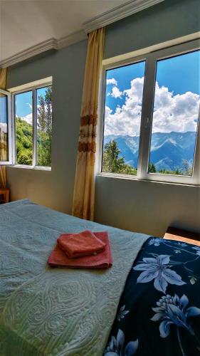 a bedroom with a bed with two red towels on it at Gujejiani Guest house in Mestia