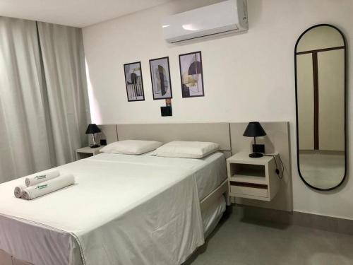 a bedroom with a white bed and a mirror at Get By Side - Jardim Oceania in Tambaú