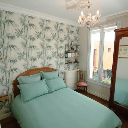 une chambre avec un grand lit blanc avec des oreillers bleus dans l'établissement Villa années 30, bords de Marne, à Joinville-le-Pont