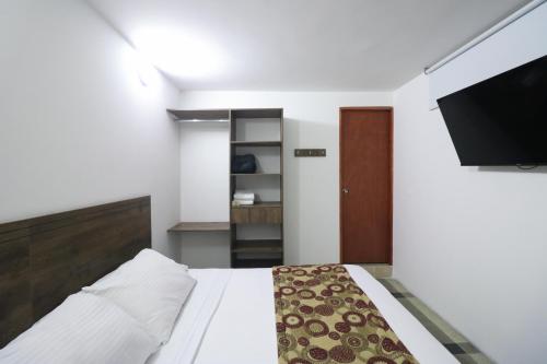 a bedroom with a bed and a flat screen tv at Hotel Boutique Estadio in Medellín