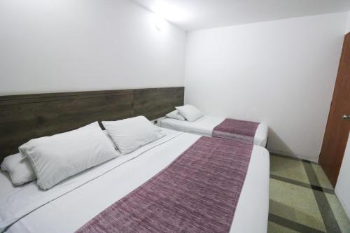 two beds in a room with white and purple at Hotel Boutique Estadio in Medellín