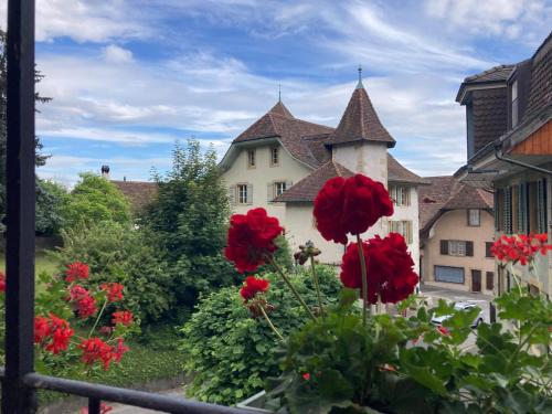 a view of a building with red flowers on a balcony at La Vigne in La Neuveville