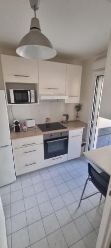 La cuisine est équipée de placards blancs et d'un four avec plaques de cuisson noires. dans l'établissement Frontière Monaco grande Terrasse, à Beausoleil