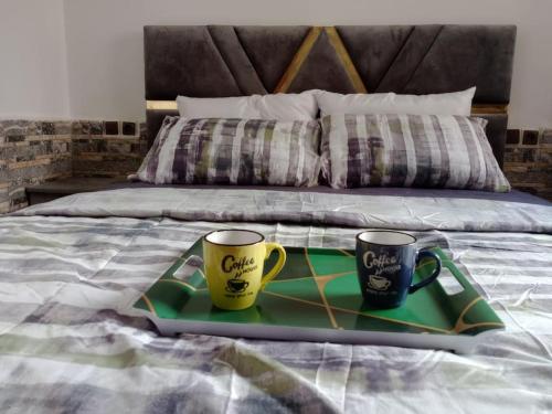 two coffee mugs sitting on a tray on a bed at Luxury Ifrane House in Ifrane