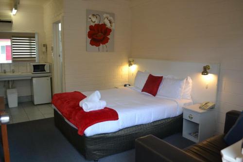 a bedroom with a large bed with a red blanket at Wattle Motel in Seymour