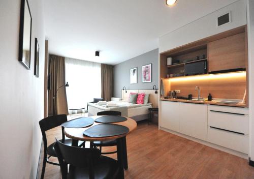 a room with a table and a kitchen and a living room at BK Aparthotel Praga - National Stadium - Comfortable Apartment for 4 people in Warsaw