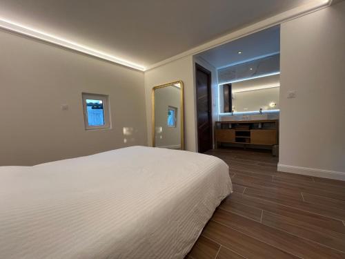une chambre avec un lit blanc et un grand miroir dans l'établissement VILLA 31 - modern suite, au Cap d'Agde