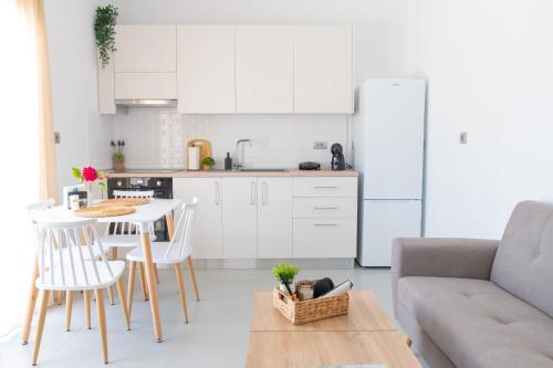 a kitchen with white cabinets and a table and a couch at AirVista Apartments in Antimácheia