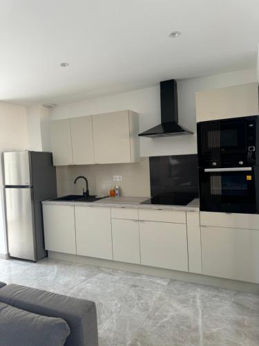 une cuisine avec des armoires blanches et un réfrigérateur en acier inoxydable dans l'établissement Superbe villa familiale jardin, à Montpellier