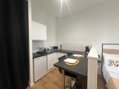 une cuisine avec un comptoir noir dans une pièce dans l'établissement Lysbed - Studio Camélia - Angers, à Angers