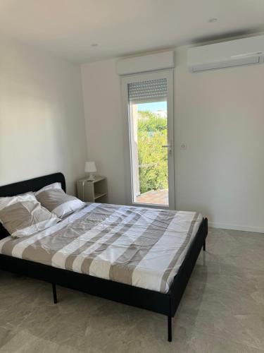 une chambre avec un grand lit avec une fenêtre dans l'établissement Superbe villa familiale jardin, à Montpellier