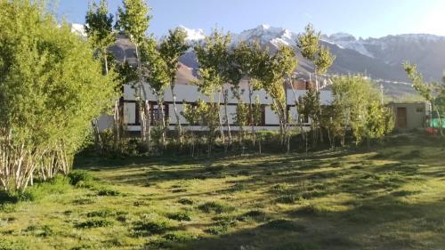 a house with trees and mountains in the background at Padmaling guest house zanskar eco camp in Padam