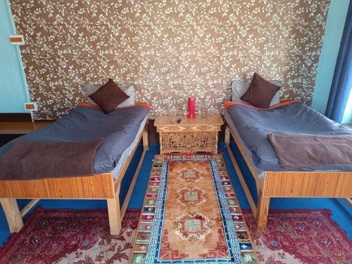 a room with two twin beds and a table at Padmaling guest house zanskar eco camp in Padam