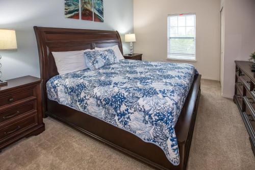 a bedroom with a bed with a blue and white bedspread at Elegant, Spacious 3bedroom Near Attractions Hot Tub Pool & Gym in Kissimmee