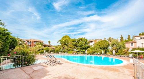 - une piscine dans un complexe avec des chaises et des arbres dans l'établissement Résidence Le Hameau de la Pinède - maeva Home - Studio 5 Personnes climatisé - Sélection MAE-0844, à Hyères