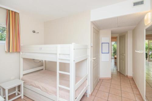 Ce lit superposé blanc se trouve dans un dortoir doté d'un couloir. dans l'établissement Résidence Le Hameau de la Pinède - maeva Home - Studio 5 Personnes climatisé - Sélection MAE-0844, à Hyères