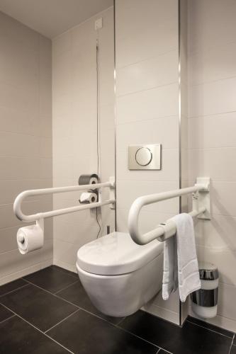 a bathroom with a white toilet and towels at Serways Hotel Bruchsal West in Forst
