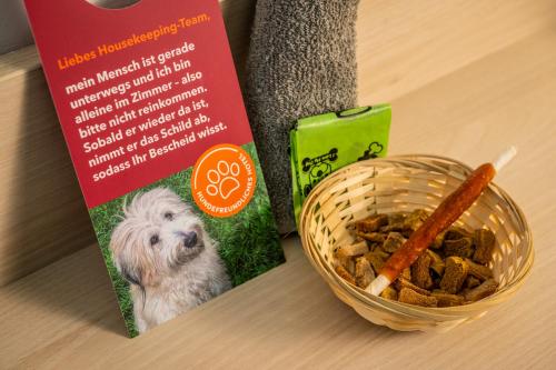 a book and a bowl of dog food next to a basket of food at Serways Hotel Bruchsal West in Forst