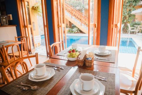 a table with plates and cups and a bowl of fruit at Pousada Mata Atlantica Juquehy in Juquei