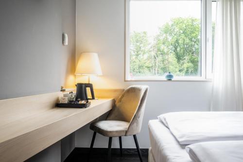 a hotel room with a desk with a chair and a window at Serways Hotel Bruchsal West in Forst