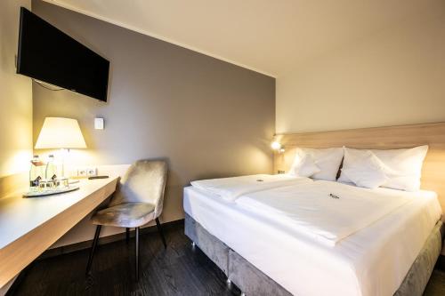 a hotel room with a bed and a desk at Serways Hotel Bruchsal West in Forst
