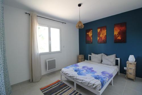 une chambre avec un lit aux murs bleus et une fenêtre dans l'établissement Villa Pinède, à Néffiès