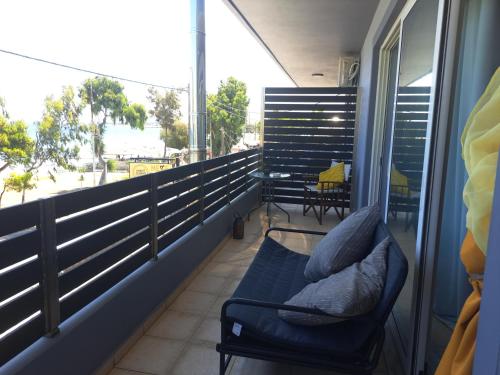 a balcony with a couch and a table and chairs at Seashell Apartment in Artemida