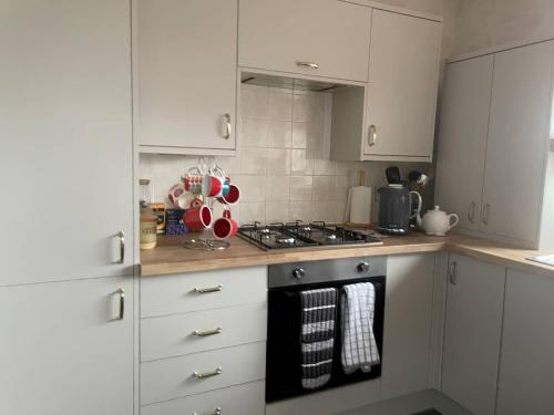 a kitchen with white cabinets and a stove top oven at Quiet secluded two bedroom bungalow with parking in Cleveleys