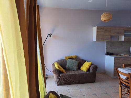 a living room with a brown couch with yellow pillows at Seashell Apartment in Artemida