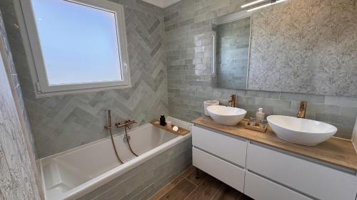 un bagno con due lavandini, una vasca e una finestra di La Villa Pangea un havre de paix unique avec vue sur la rivière et la nature a Gignac