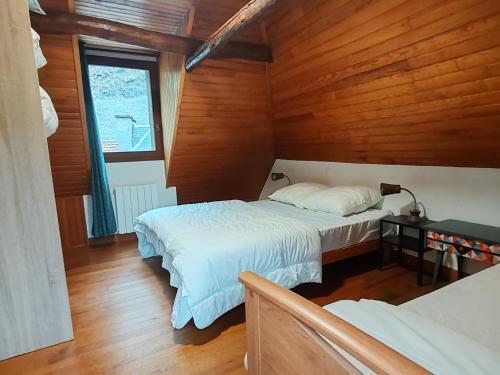 - une chambre avec 2 lits dans une pièce dotée de murs en bois dans l'établissement Maison 13 pers à 10mn de Luchon, à Cazaux-Layrisse