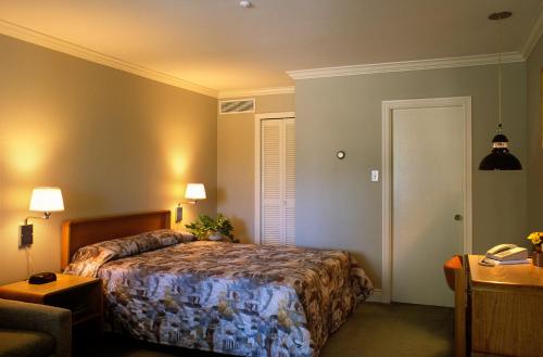 a bedroom with a bed and a desk and a chair at Auberge De La Baie in Caraquet