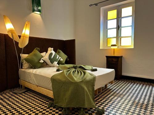 a bedroom with a bed with green pillows and a window at Cosy spacious apartments medina center in Essaouira