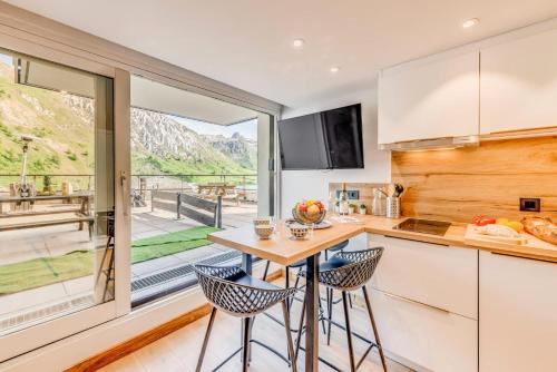 une cuisine avec une table et des chaises ainsi qu'une grande fenêtre dans l'établissement Résidence Palafour - Studio chaleureux, terrasse vue lac MAE-3398, à Tignes