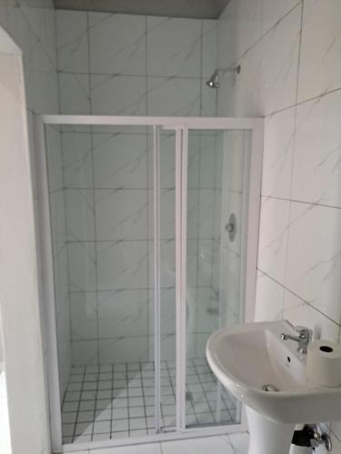 a white bathroom with a shower and a sink at Randhart guesthouse in Alberton