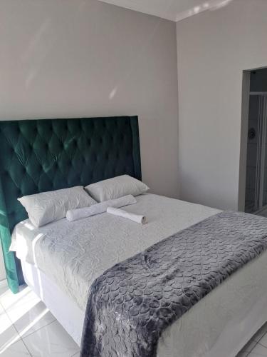 a bedroom with a large bed with a green headboard at Randhart guesthouse in Alberton